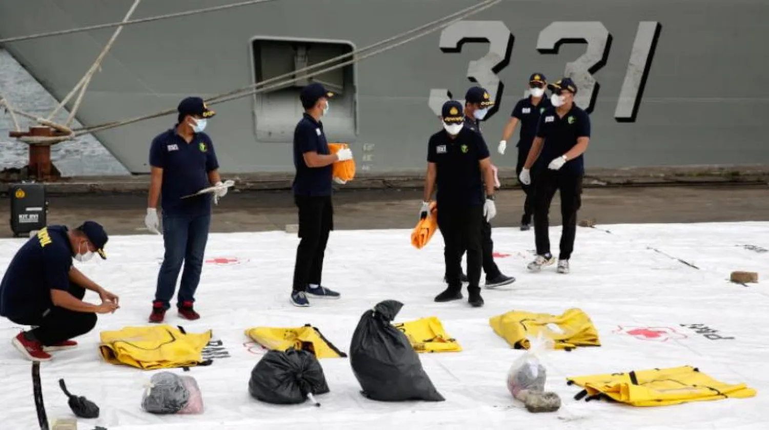 Endonezya'daki soruşturma ekibi üyeleri düşen uçağın kurbanlarının parçalarının yer aldığı çantaları inceliyor. (EPA) 