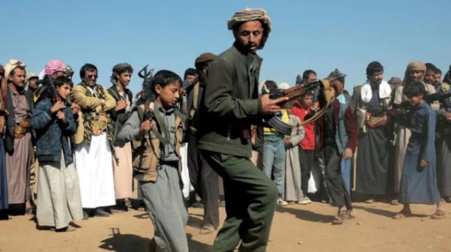أرشيفية لطفل في صفوف الحوثيين يستعرض سلاحه مع مجموعة من المقاتلين في صنعاء (غيتي)