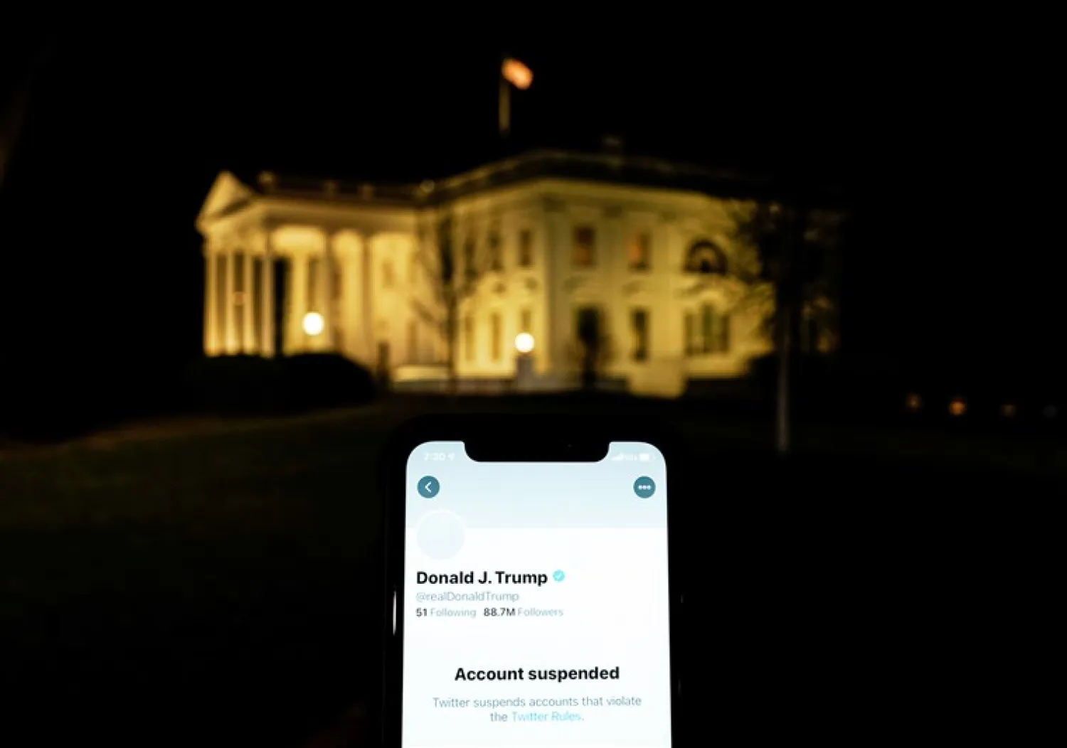 A photo illustration shows the suspended Twitter account of US President Donald Trump on a smartphone and the White House in Washington, US, January 8, 2021. REUTERS/Joshua Roberts/Illustration