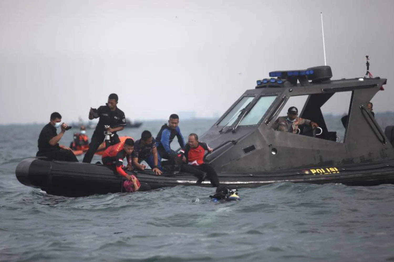 غواصون ينقلون أكياساً مليئة بالحطام إلى قارب بحث وإنقاذ من رحلة سريويجايا الجوية SJ182 في ميناء تانجونج بريوك شمال جاكرتا (أ.ف.ب)