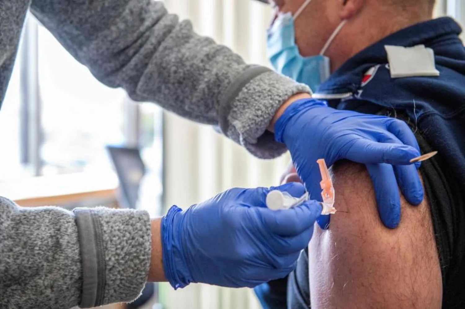 ممرضة أميركية تحقن رجل إطفاء بلقاح «مودرنا» ضد «كوفيد - 19» في مستشفى بولاية ماساتشوستس (أ.ف.ب)