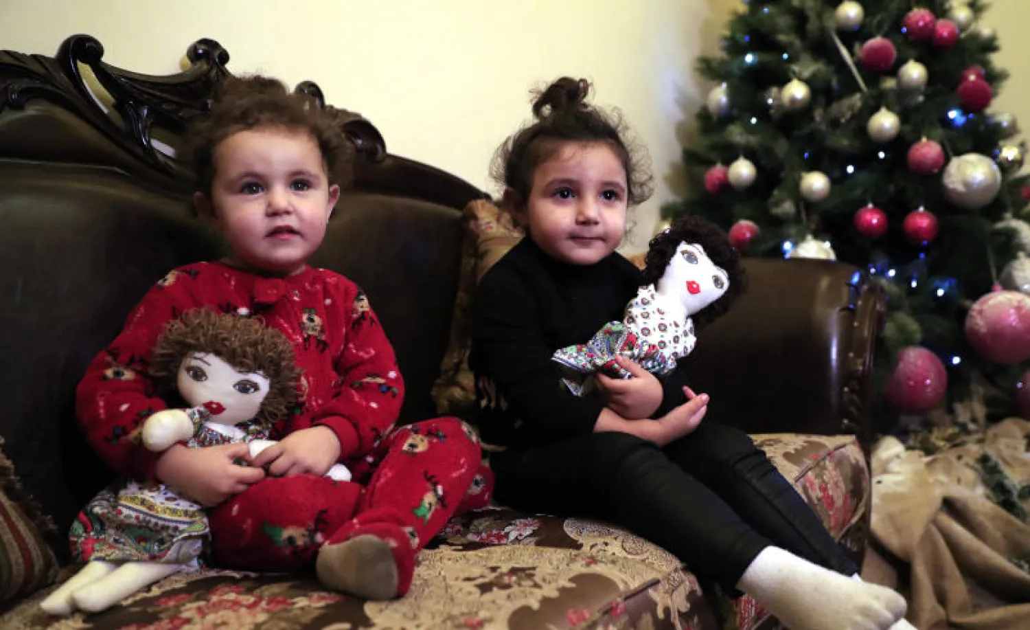 طفلتان لبنانيتان تحملان لعبتيهما بعدما تضرر منزلهما في إنفجار مرفأ بيروت (أ.ب)