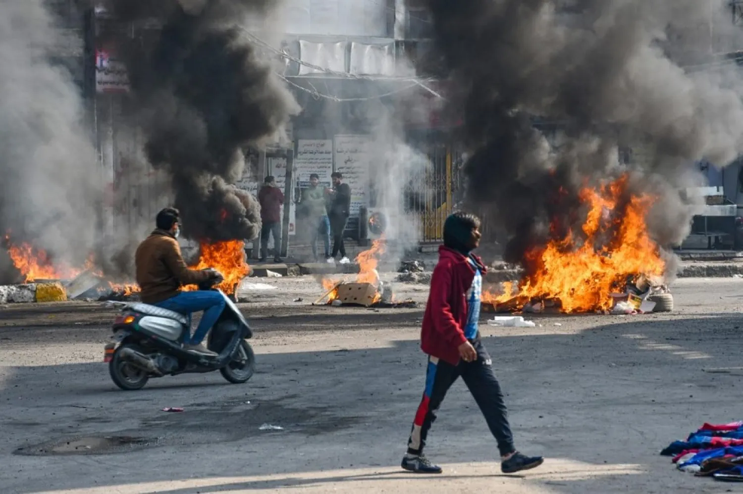 Iraqi protesters are pictured next to burning tires during clashes with police during anti-government demonstrations in Nasiriyah, southern Iraq, on January 10, 2021. (AFP)