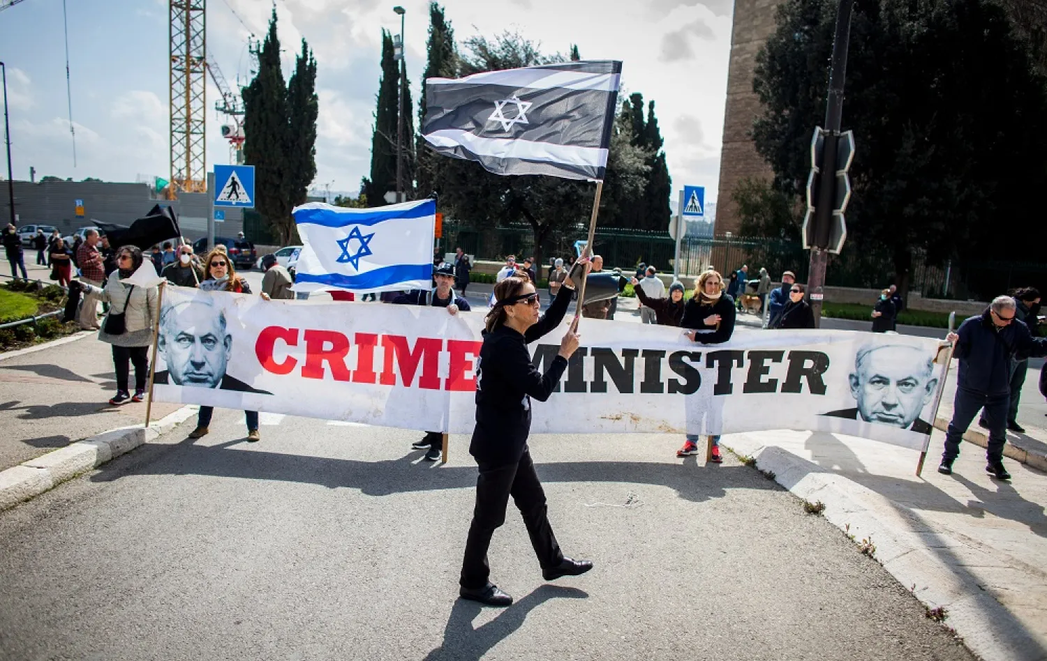 People wave Israeli flags during a protest outside the Israeli parliament, Jerusalem, Thursday, March 19, 2020. (AP)
