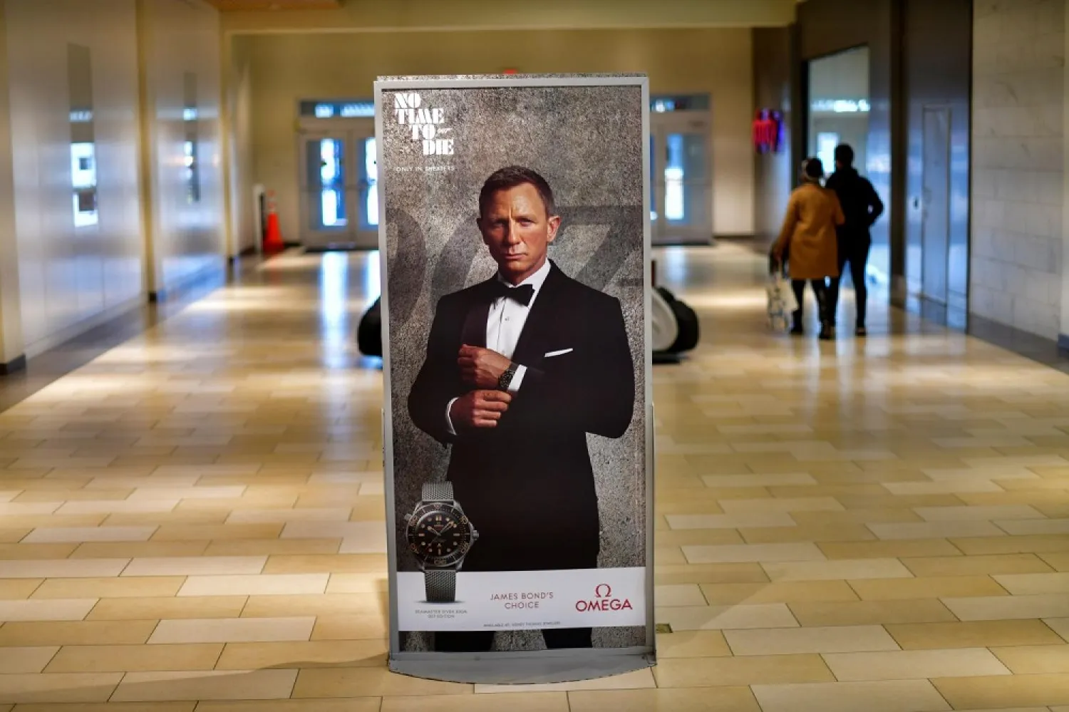 Shoppers walk past an ad for the upcoming James Bond film whose release has been delayed due to the pandemic, at the Christiana Mall in Newark, Delaware US November 19, 2020. (Reuters)