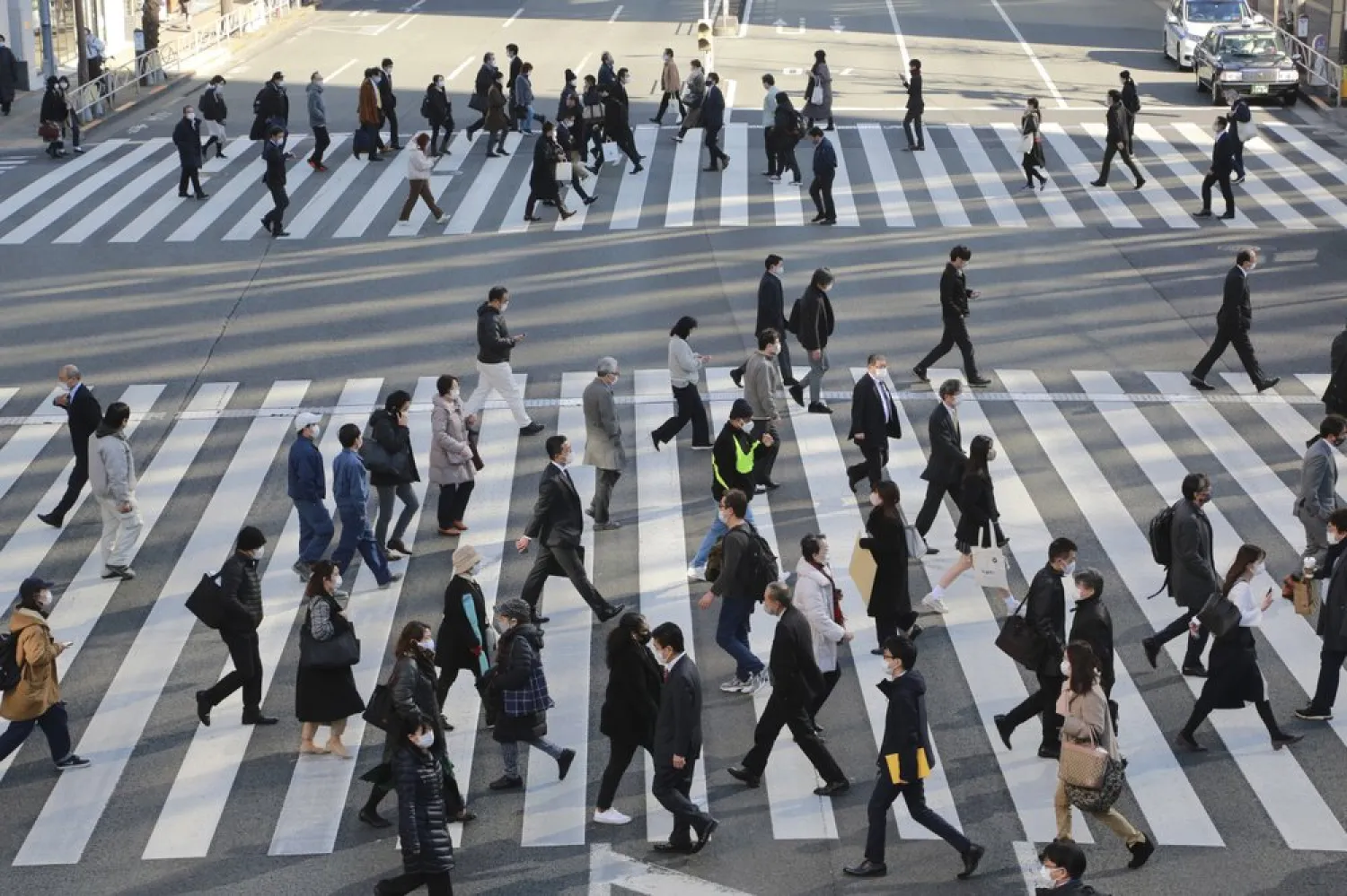 People wearing face masks to protect against the spread of the coronavirus cross an intersection on a street in Tokyo, Wednesday, Jan. 13, 2021. AP Photo/Koji Sasahara

