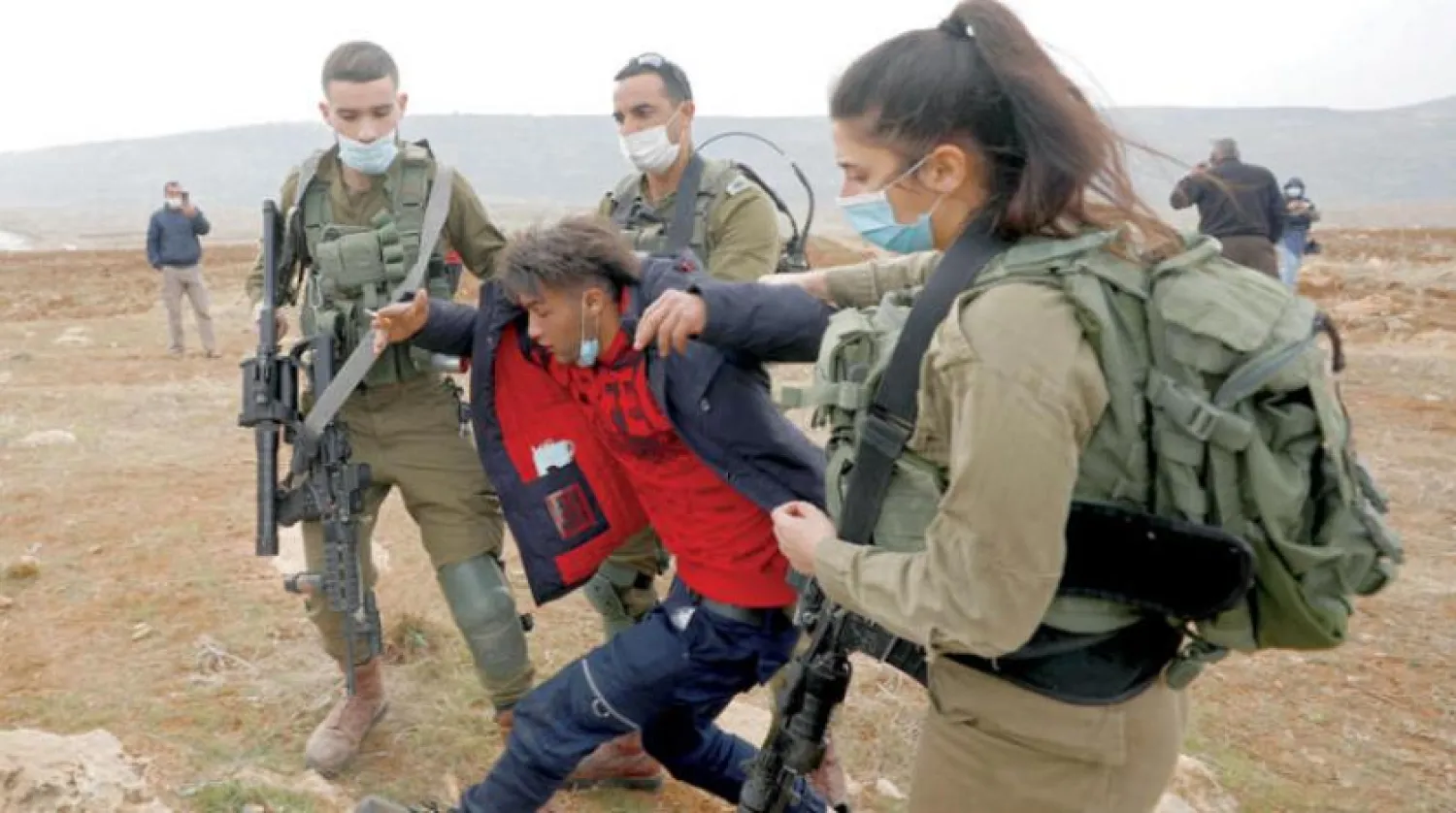 İsrail askerleri Nablus yakınlarındaki Akraba'da yerleşimlere karşı düzenlenen protestolar sırasında bir göstericiyi tutukladı. (Reuters)