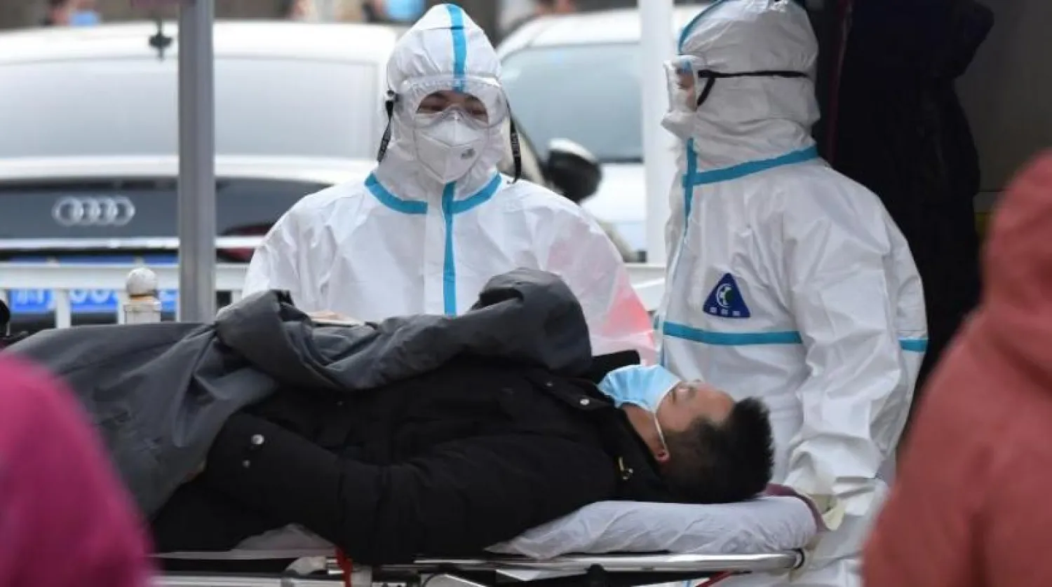 Koruyucu giysiler giyen iki sağlık çalışanı, "Koronalı" bir hastayı Pekin'deki bir hastaneye naklediyor. (AFP)
