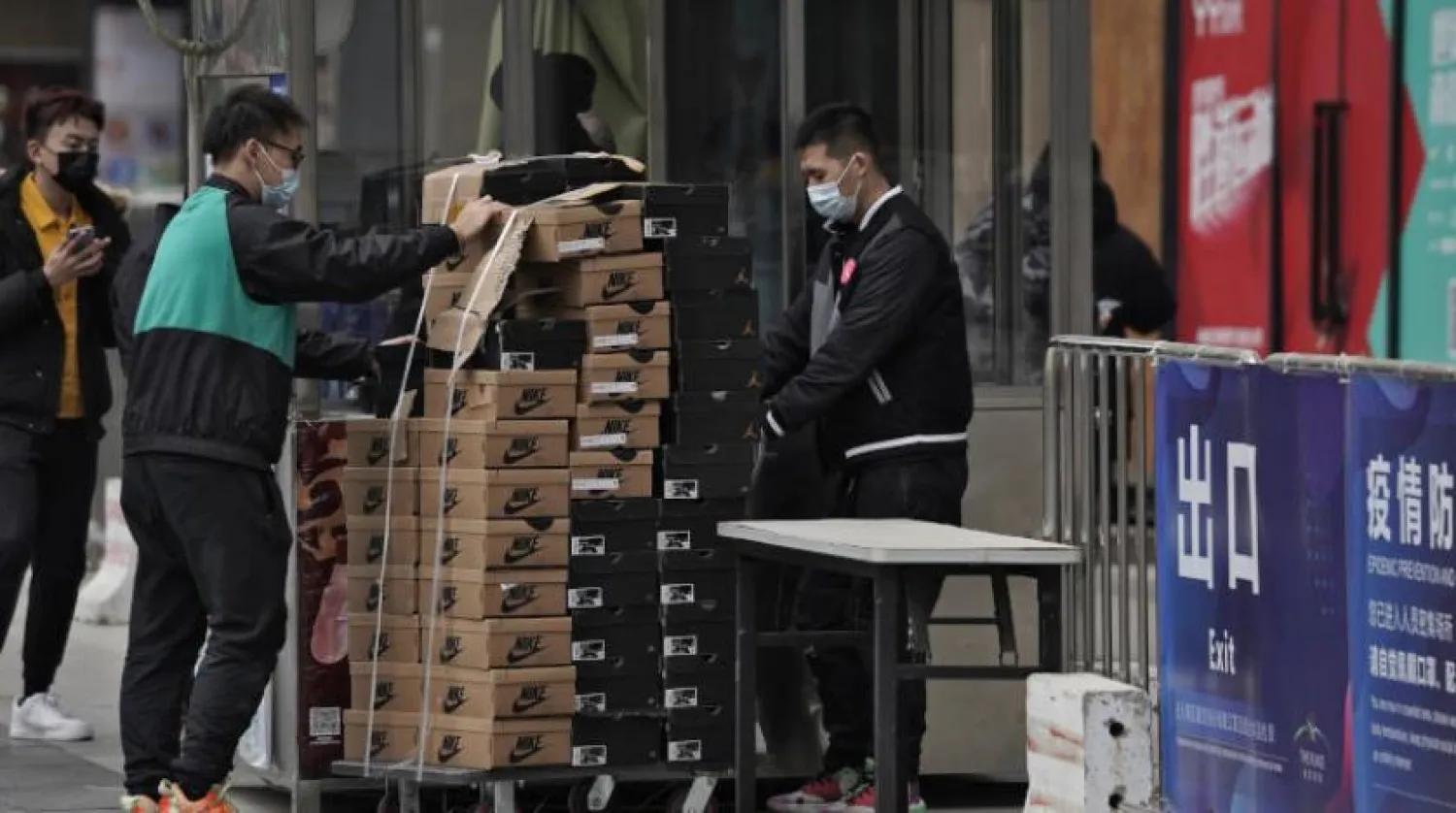 Pekin’de bir ayakkabı mağazasında maskeleriyle çalışan işçiler kutuları taşıyor. (AP)