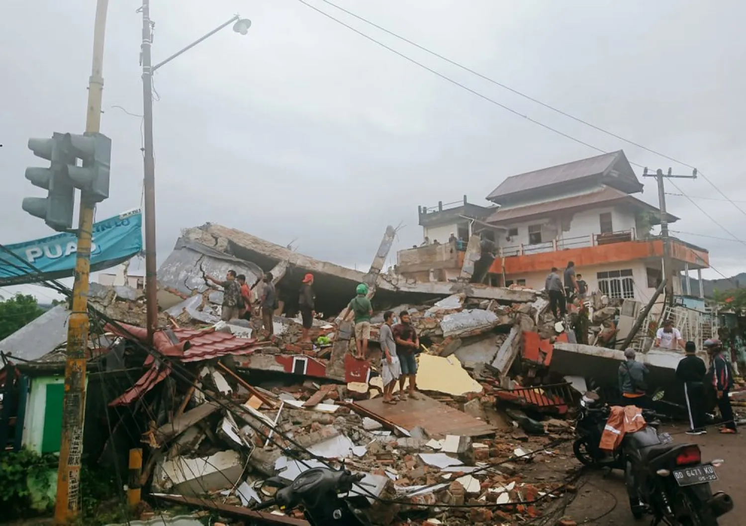 Residents inspect earthquake-damaged buildings in Mamuju, West Sulawesi, Indonesia, Friday, Jan. 15, 2021. A strong inland and shallow earthquake hit eastern Indonesia early Friday causing people to panic in parts of the country's Sulawesi island and run to higher ground. (AP Photo/Rudy Akdyaksyah)

