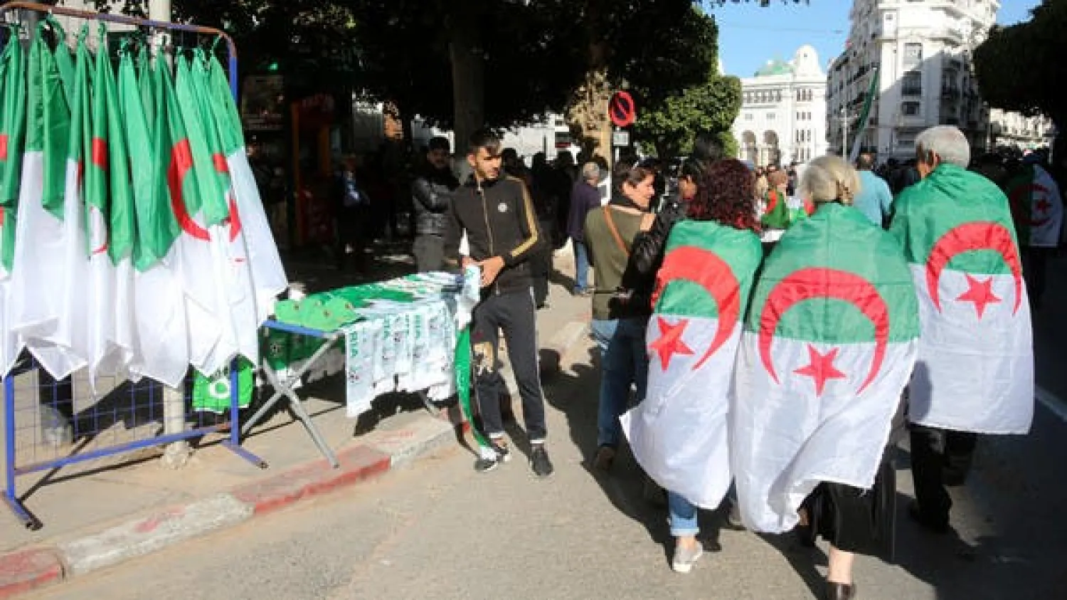  A file photo shows demonstrators wearing national flags walk past a street vendor during a protest demanding a change of the power structure in Algiers, Algeria January 24, 2020. (Reuters)

