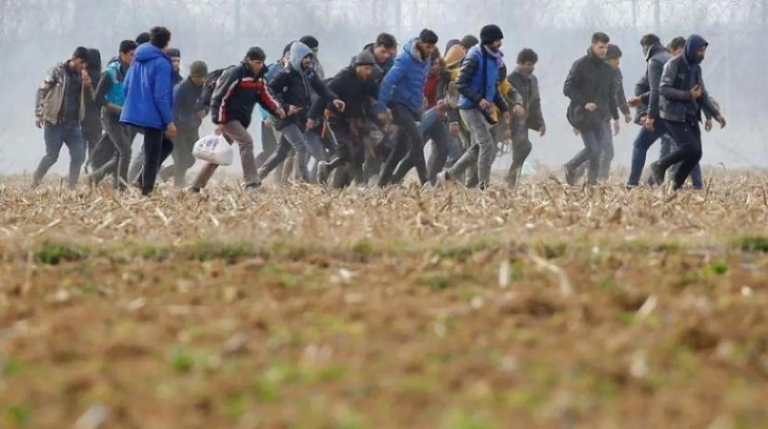 Göçmenler, Yunanistan ile Pazarkule sınır kapısının yakınında yaralı bir kişiyi taşıyor (Reuters-Arşiv)