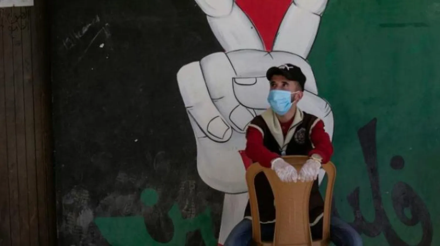 فلسطيني يضع القفازات وكمامة خوفاً من كورونا (أ.ف.ب)