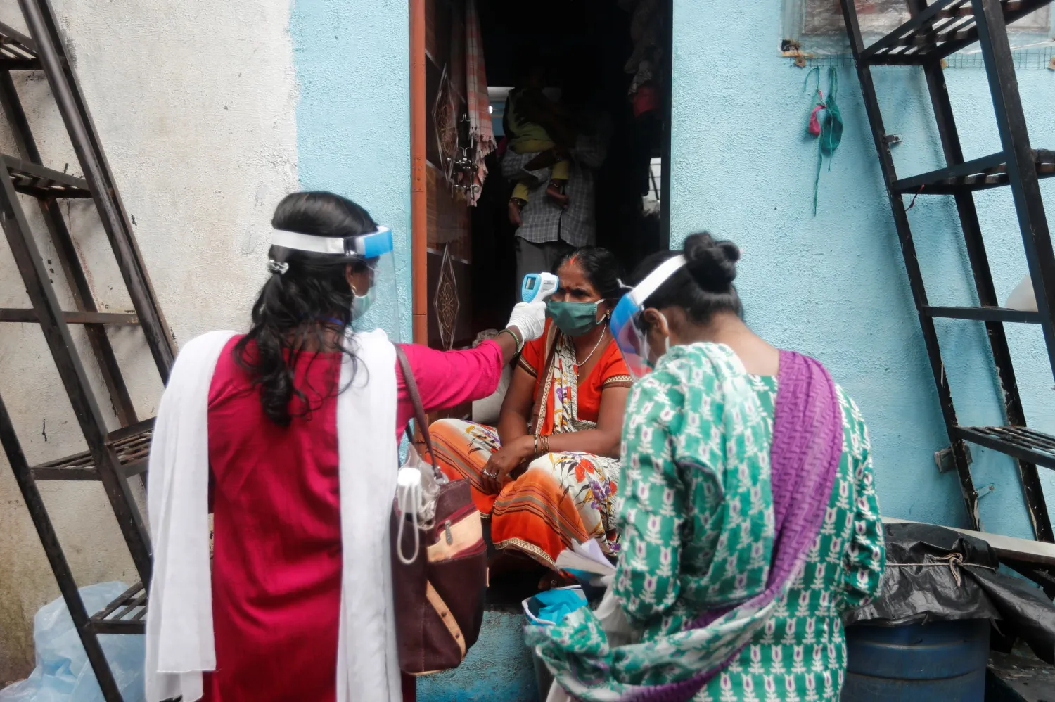 Community health volunteers check the temperature of a woman during a check up campaign for the coronavirus disease (COVID-19), at a slum in Mumbai, India, August 16, 2020. (Reuters)