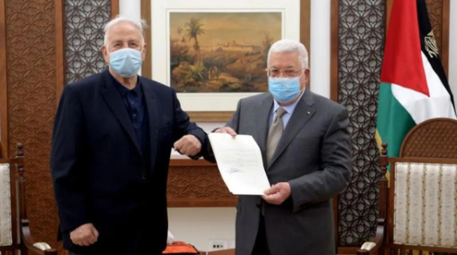 الرئيس الفلسطيني محمود عباس يحمل مرسوم الانتخابات إلى جانب رئيس لجنة الانتخابات حنا ناصر في رام الله  (أ.ف.ب)