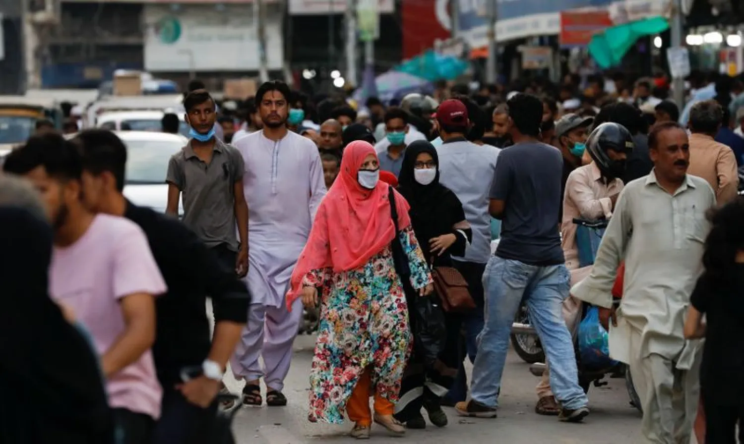 Women wearing protective face masks walk amid the rush of people along a road as the outbreak of the coronavirus disease (COVID-19) continues, in Karachi | Photo: REUTERS
