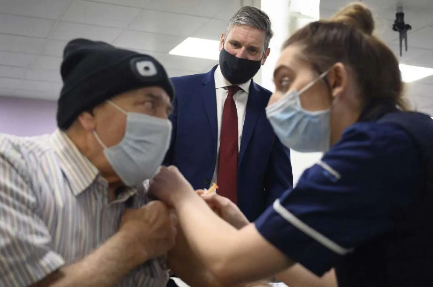 Britain's Labour leader Sir Keir Starmer watches as Melvin Allanson receives the first of two COVID-19 vaccination shots during a visit to the vaccination centre at Robertson House, in Stevenage, England, Thursday, Jan. 14, 2021. (Leon Neal/Pool Photo via AP)
