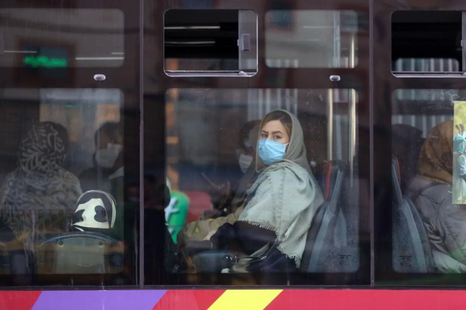 سيدة إيرانية ترتدي قناعاً واقياً على متن حافلة في طهران (أ.ف.ب)