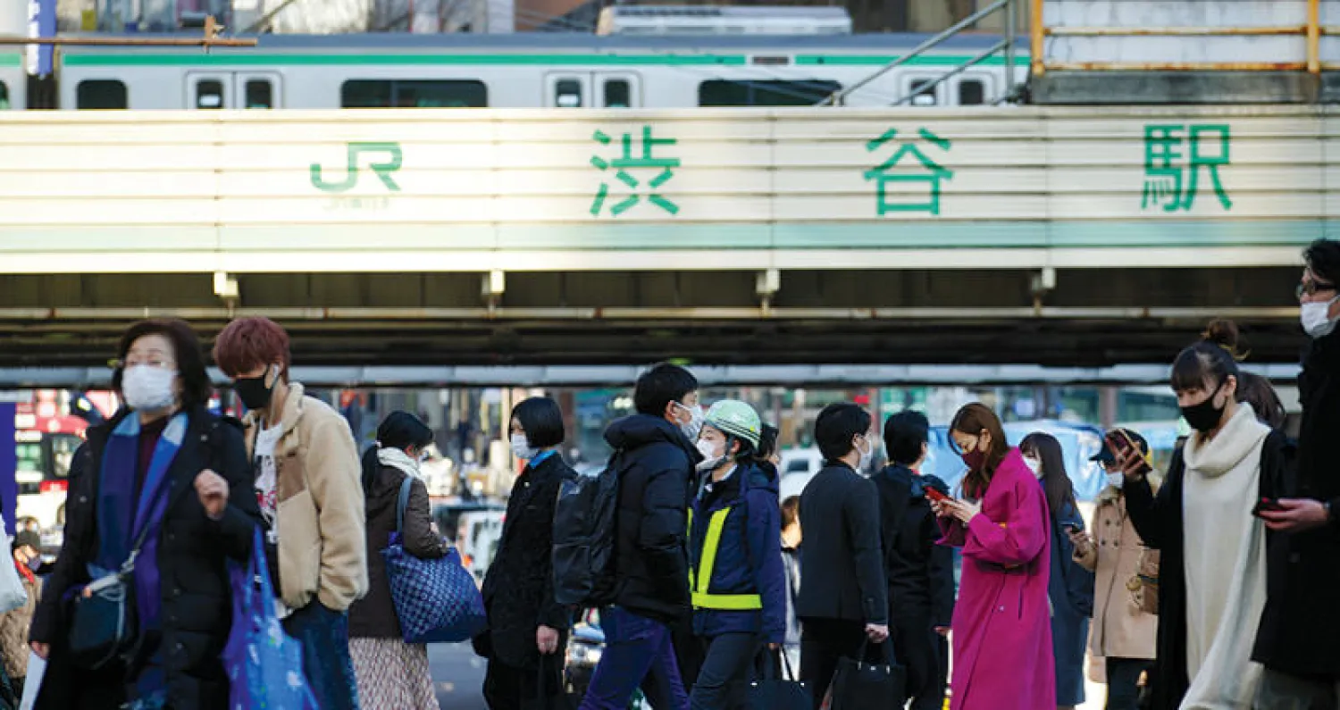 يابانيون يعبرون منطقة مشاة في إحدى ضواحي طوكيو والأقنعة تغطي وجوههم أمس (أ.ب)