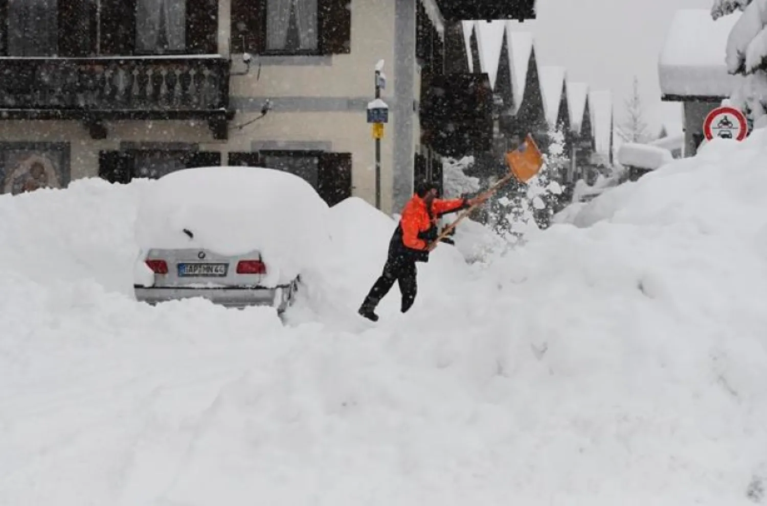 A man shovels his car free of snow after days of snowfall in Garmisch-Partenkirchen, southern Germany, Monday, Jan. 18, 2021. (Angelika Warmuth/dpa via AP)
