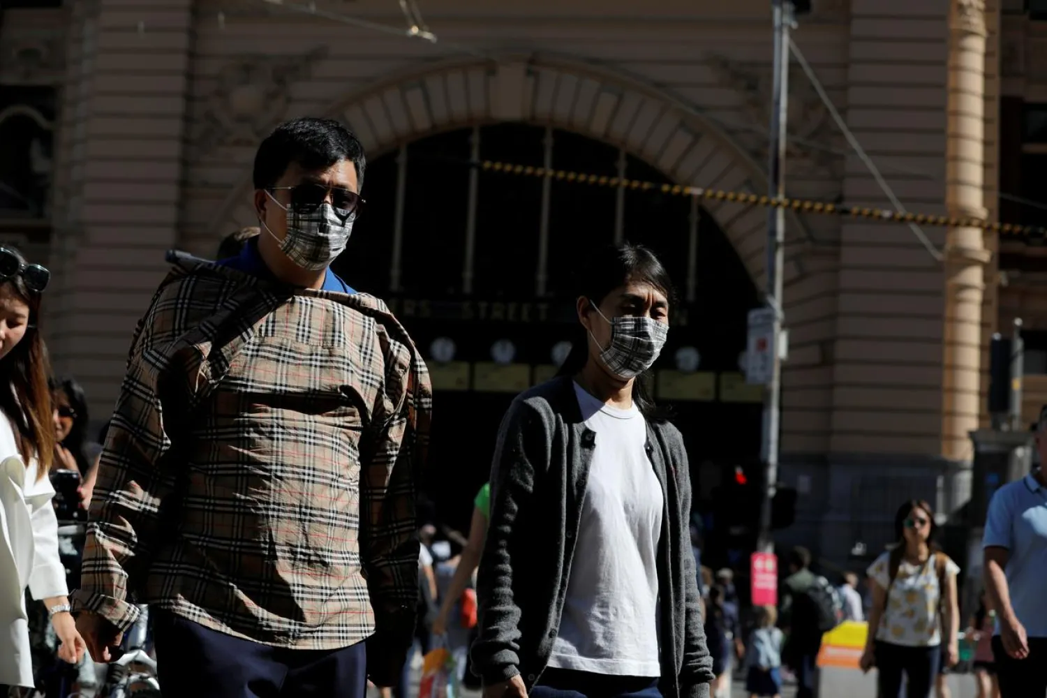 FILE PHOTO: People wearing face masks walk by Flinders Street Station after cases of the coronavirus were confirmed in Melbourne, Victoria, Australia, January 29, 2020. REUTERS/Andrew Kelly
