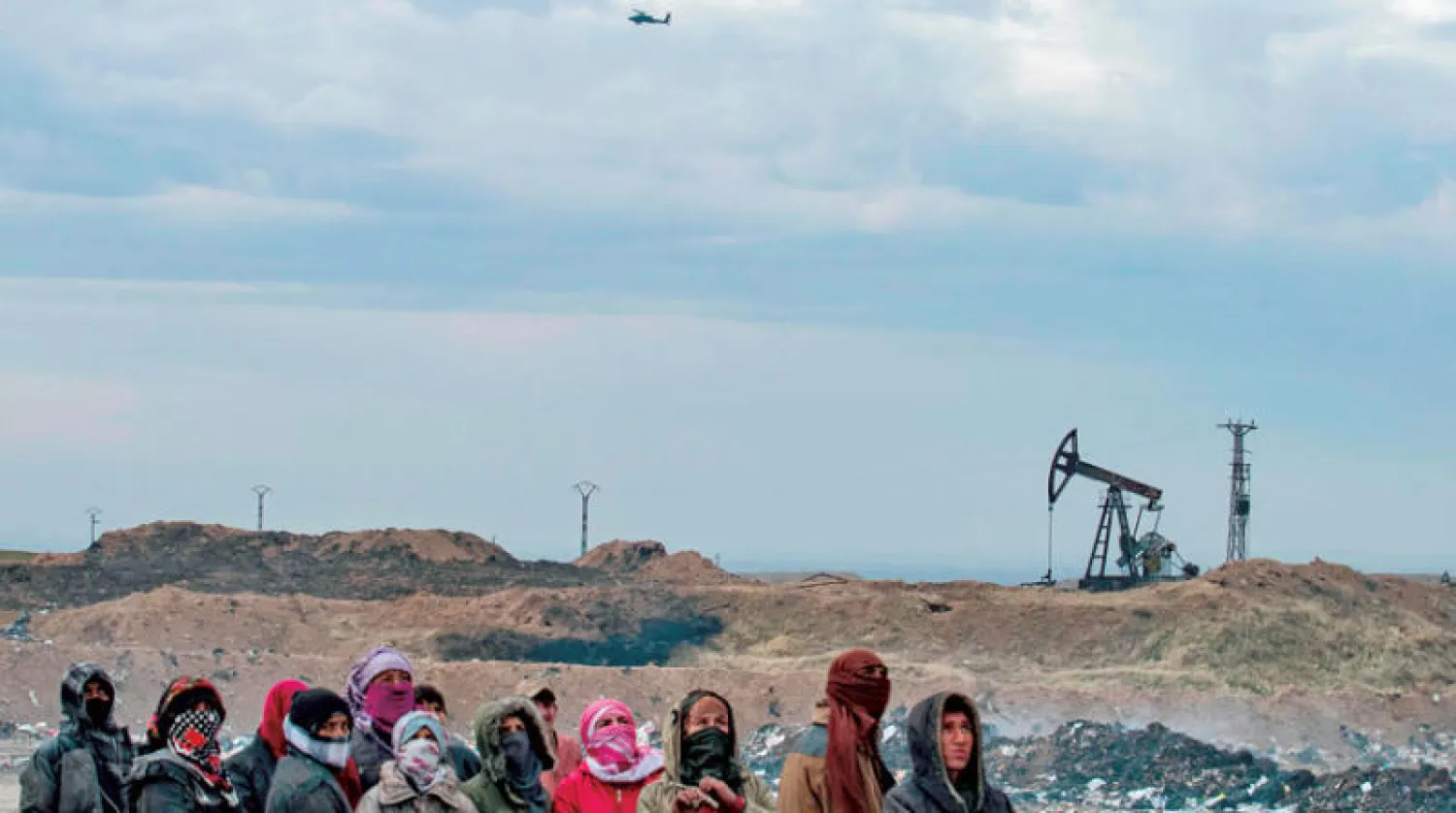 سوريون قرب حقل نفطي في ريف المالكية بشمال شرقي سوريا يوم الأحد (أ.ف.ب)