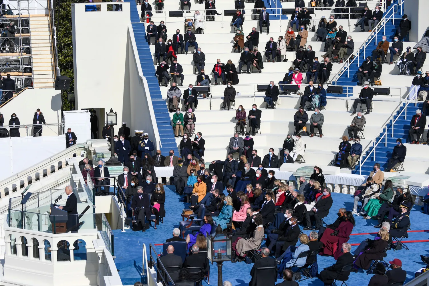 مجموعة من الحضور يجلسون في مقاعد متفرقة متبعين قواعد التباعد الاجتماعي (أ.ب)