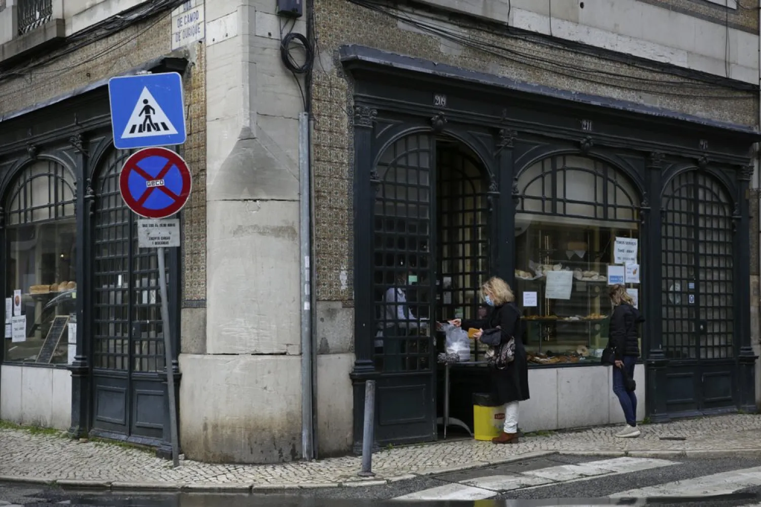 A woman buys food at the door of a pastry shop in Lisbon, Wednesday, Jan. 20, 2021. (AP)