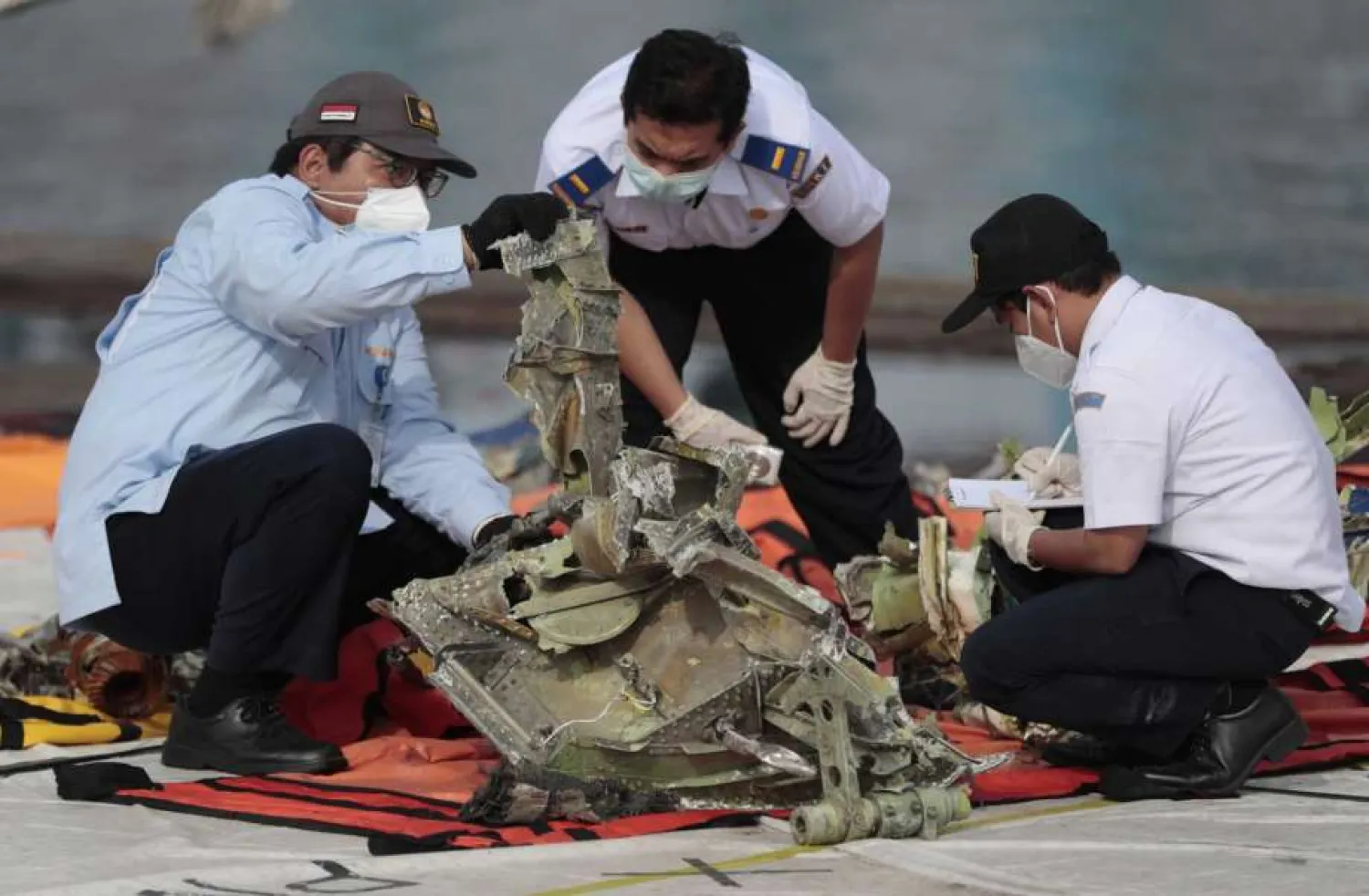 Investigators inspect pieces of the Sriwijaya Air flight SJ-182 retrieved from the Java Sea where the passenger jet crashed on Jan. 9, at Tanjung Priok Port in Jakarta, Indonesia, Thursday, Jan. 21, 2021. (AP Photo/Dita Alangkara)
