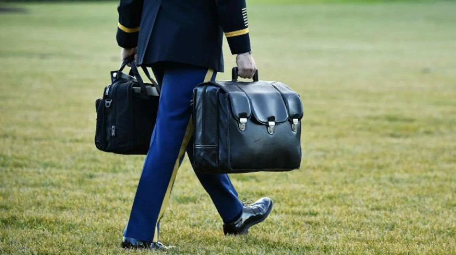 یک دستیار نظامی کیف هسته‌ای را در حالی حمل می‌کند که رئیس‌جمهور سابق آمریکا کاخ سفید را ترک می‌کند (AFP)
