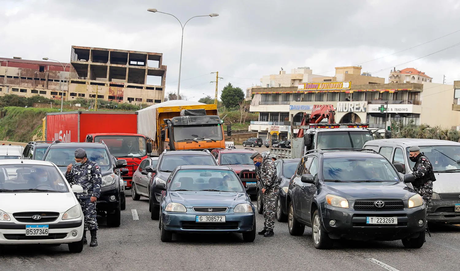 Members of the Lebanese security forces check citizens' documents at a COVID-19 checkpoint near the coastal town of Safra on the Tripoli-Beirut main highway on January 19, 2021, as Lebanon enters a second week under lockdown aimed at preventing the country's creaking healthcare system from collapsing. (Photo by JOSEPH EID / AFP)