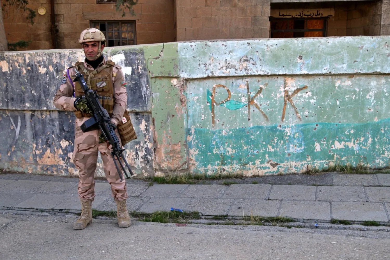 An Iraqi army soldier stands next to the graffiti left by PKK members, who recently withdrew in Sinjar, Iraq. Dec. 4, 2020. (AP File Photo)