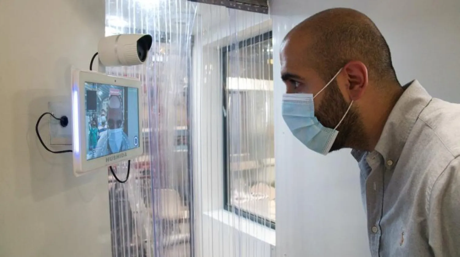 In this Monday, April 27, 2020 photo, a worker examines a gate system made by Guard ME that conducts temperature checks and fogs disinfectants on users, in Dubai, United Arab Emirates. (AP Photo/Jon Gambrell)
