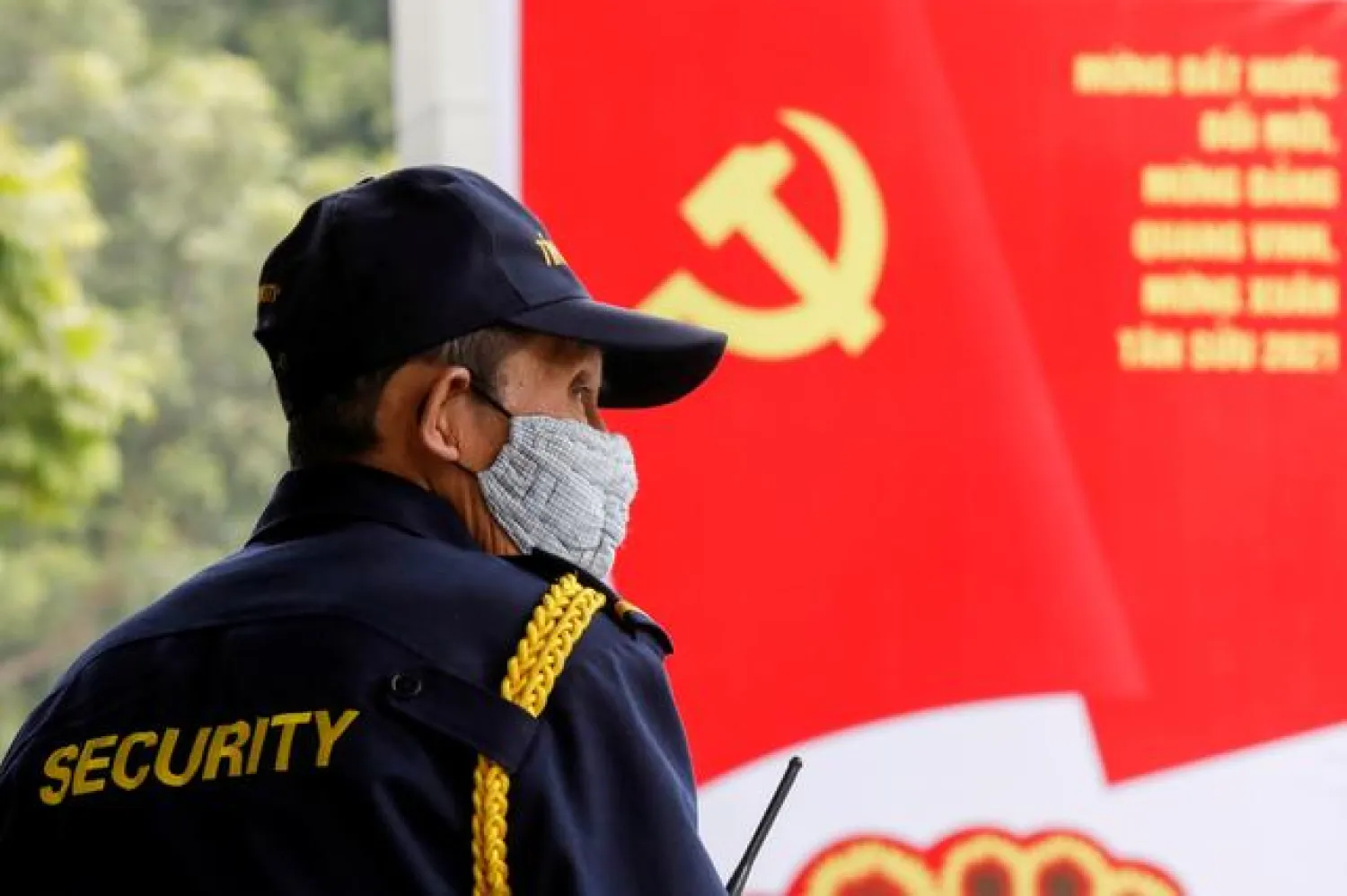 FILE PHOTO: A security officer stands guard near a poster for the upcoming 13th National Congress of the ruling Communist Party of Vietnam, on a street in Hanoi, Vietnam January 12, 2021. REUTERS/Kham
