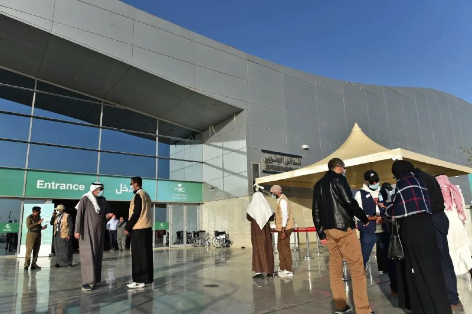 أشخاص خارج مركز الرياض الدولي للمؤتمرات والمعارض قبل تلقيهم جرعة لقاح ضد الفيروس (أ.ف.ب)