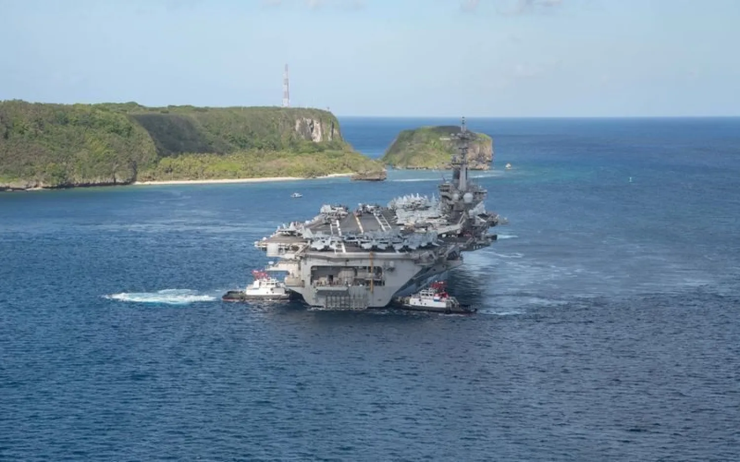 The US Navy aircraft carrier USS Theodore Roosevelt departs following an extended visit in the midst of a coronavirus outbreak, from Apra Harbor, Guam May 21, 2020. (Handout via Reuters)