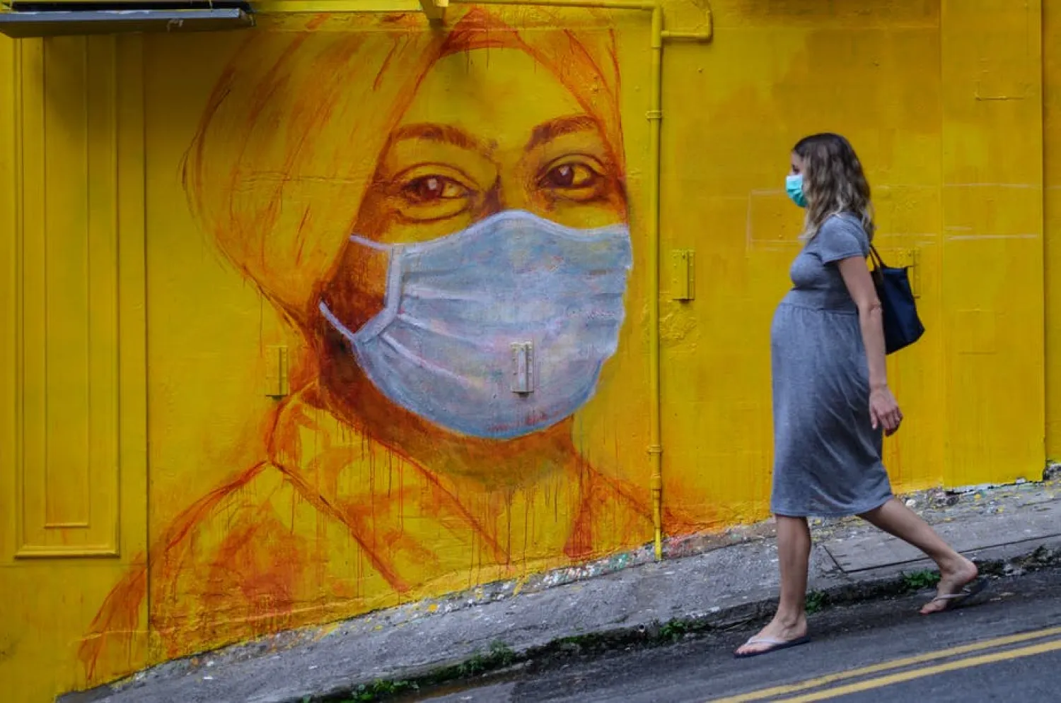 A pregnant woman walks past a street mural in Hong Kong on March 23, 2020. (Getty Images)