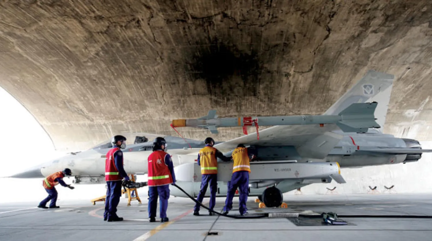 عسكريون يجهّزون طائرة حربية بصواريخ استعداداً لتدريب يحاكي حالة حرب بمدينة تاينان في تايوان أمس (إ.ب.أ)
