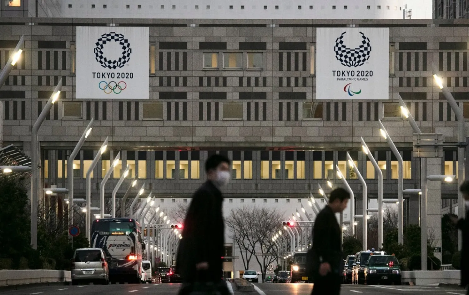 People walk across a pedestrian crossing near the Tokyo Metropolitan Government building adorned with signs promoting the 2020 Olympics. (AP)