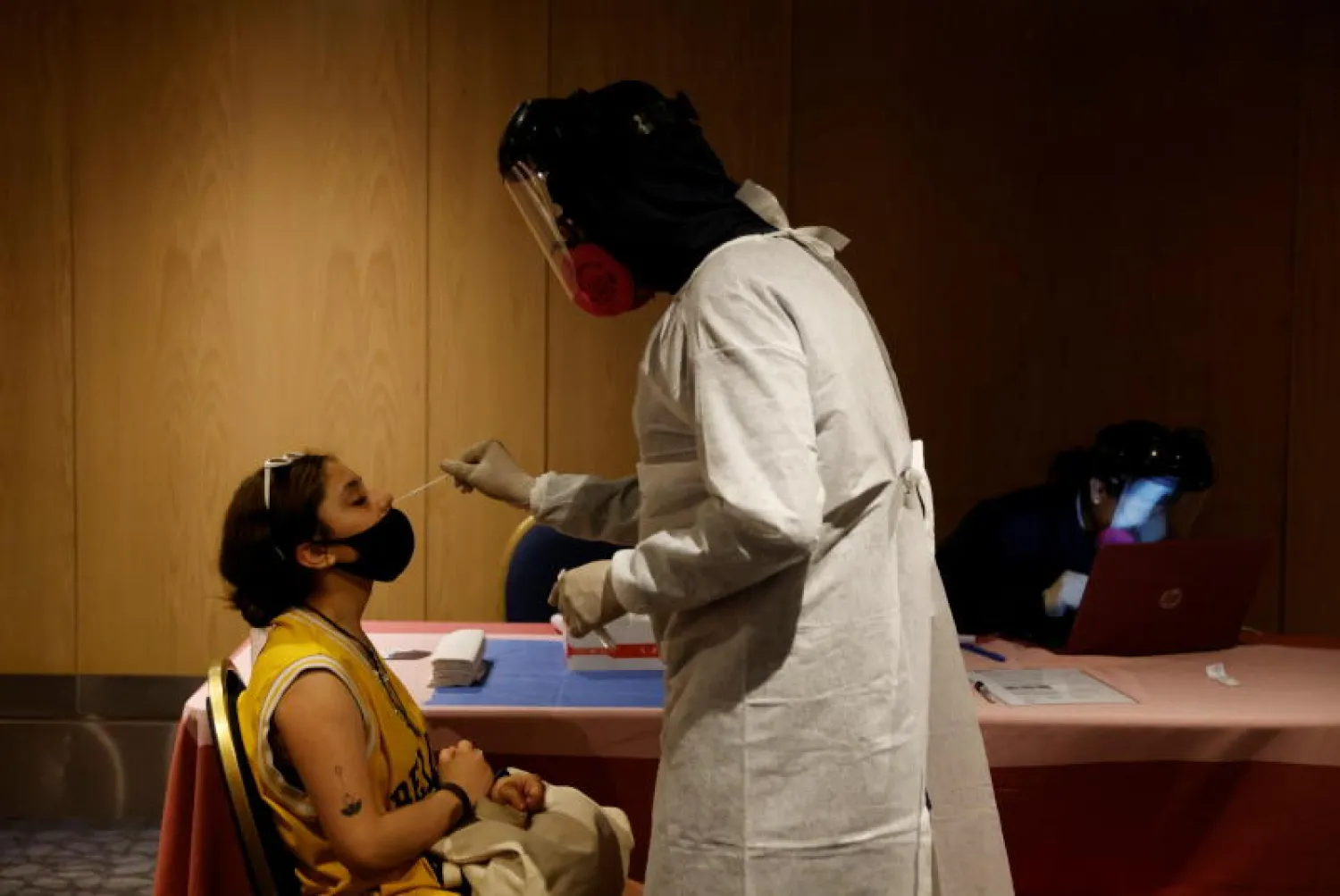 عامل رعاية صحية يرتدي معدات الحماية الشخصية يأخذ عينة مسحة من أحد الركاب في مكسيكو سيتي (رويترز)