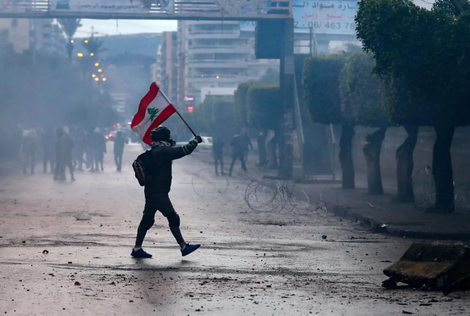 محتج يرفع العلم اللبناني خارج السراي في طرابلس (أ.ف.ب)