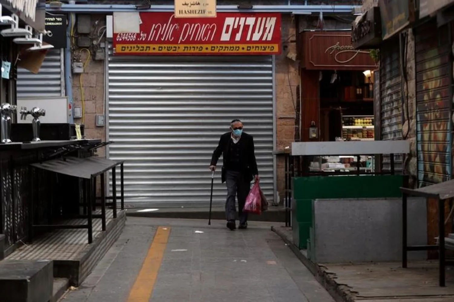 FILE PHOTO: A man carries shopping bags inside a market, as Israel tightens a national lockdown in a bid to curb a sharp rise in new coronavirus disease (COVID-19) infections, in Jerusalem January 8, 2021. REUTERS/Ronen Zvulun
