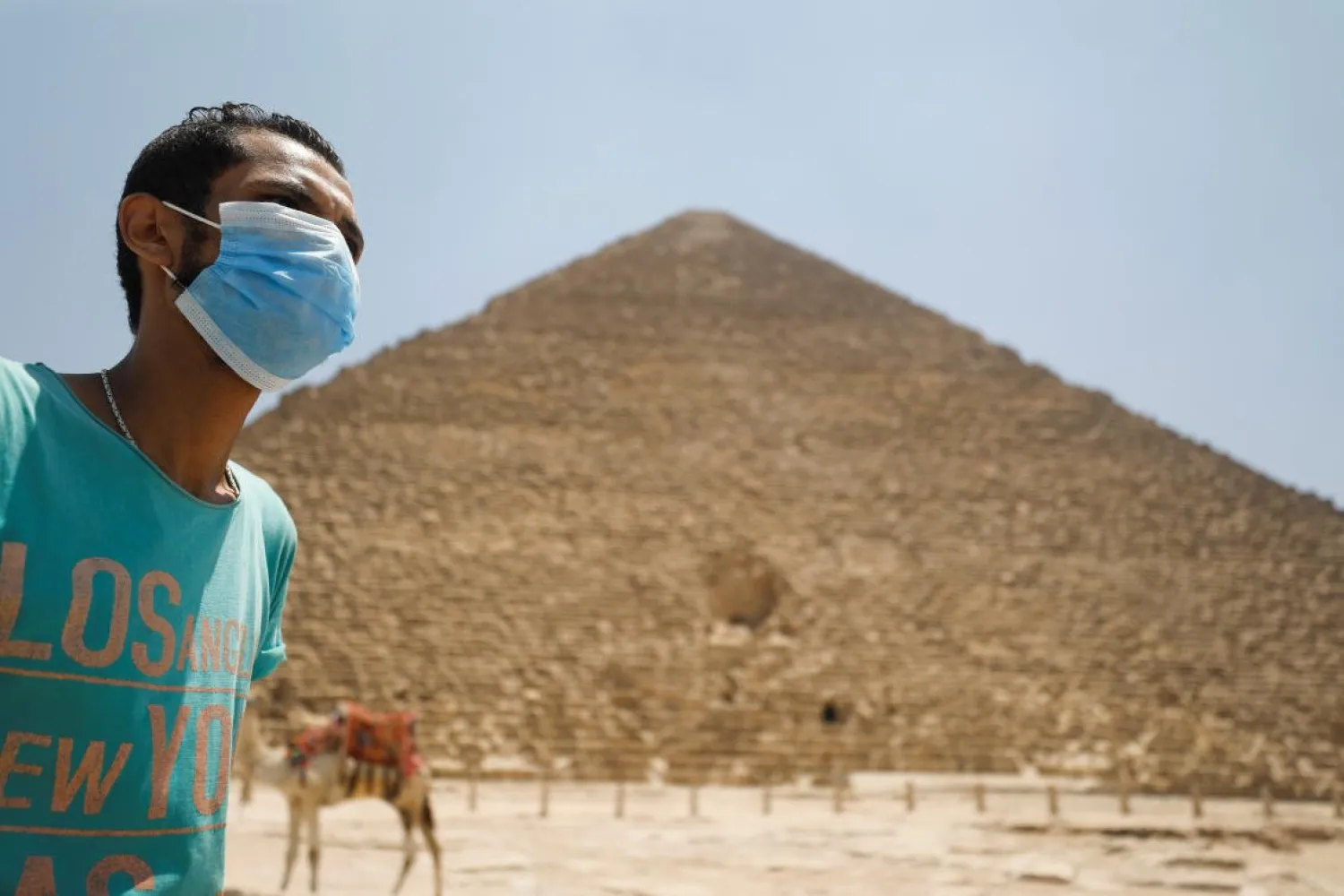 A man wearing a face mask is seen in front of the Great Pyramids of Giza after reopening for tourist visits, following the outbreak of the coronavirus disease (COVID-19), in Cairo, Egypt July 1, 2020. Reuters