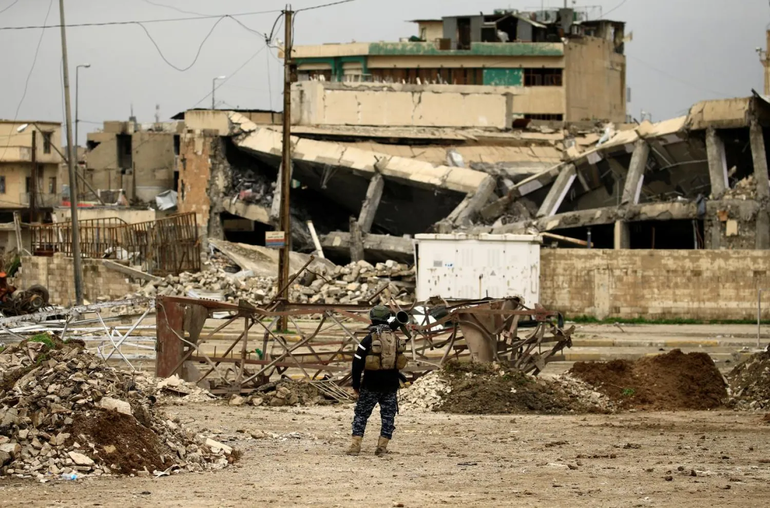 A federal policeman carries his weapon as he stands near buildings destroyed in clashes during a battle against ISIS militants, in Mosul. REUTERS/Thaier Al-Sudani