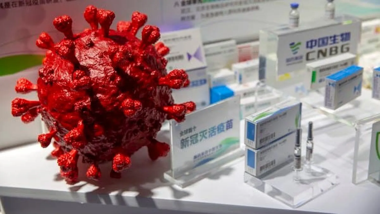 A model of a coronavirus is displayed next to boxes for COVID-19 vaccines at an exhibit by Chinese pharmaceutical firm Sinopharm in Beijing, Sept. 5, 2020. AP
