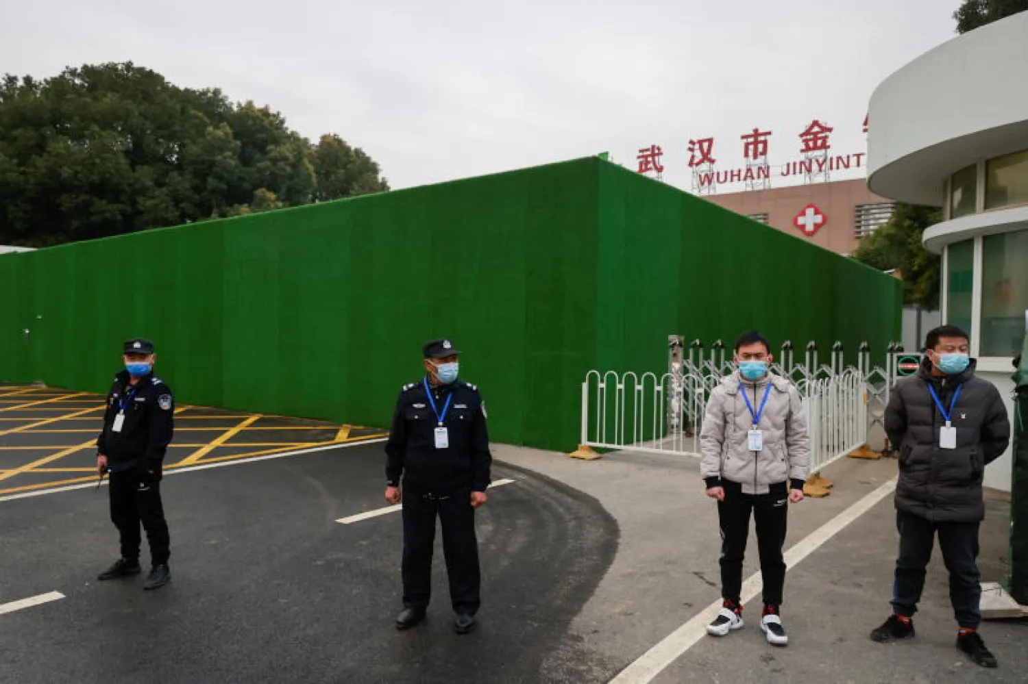 حراس الأمن يقفون خارج مستشفى جينينتان بعد دخول فريق من منظمة الصحة العالمية مجمعه في ووهان (رويترز)