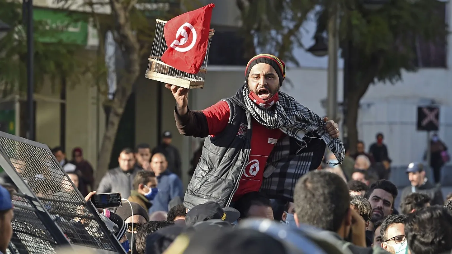 A Tunisian protester lifts a flag-clad birdcage during an anti-government demonstration on Habib Bourguiba Avenue in the capital Tunis, on Jan. 19, 2021. (Getty Images)