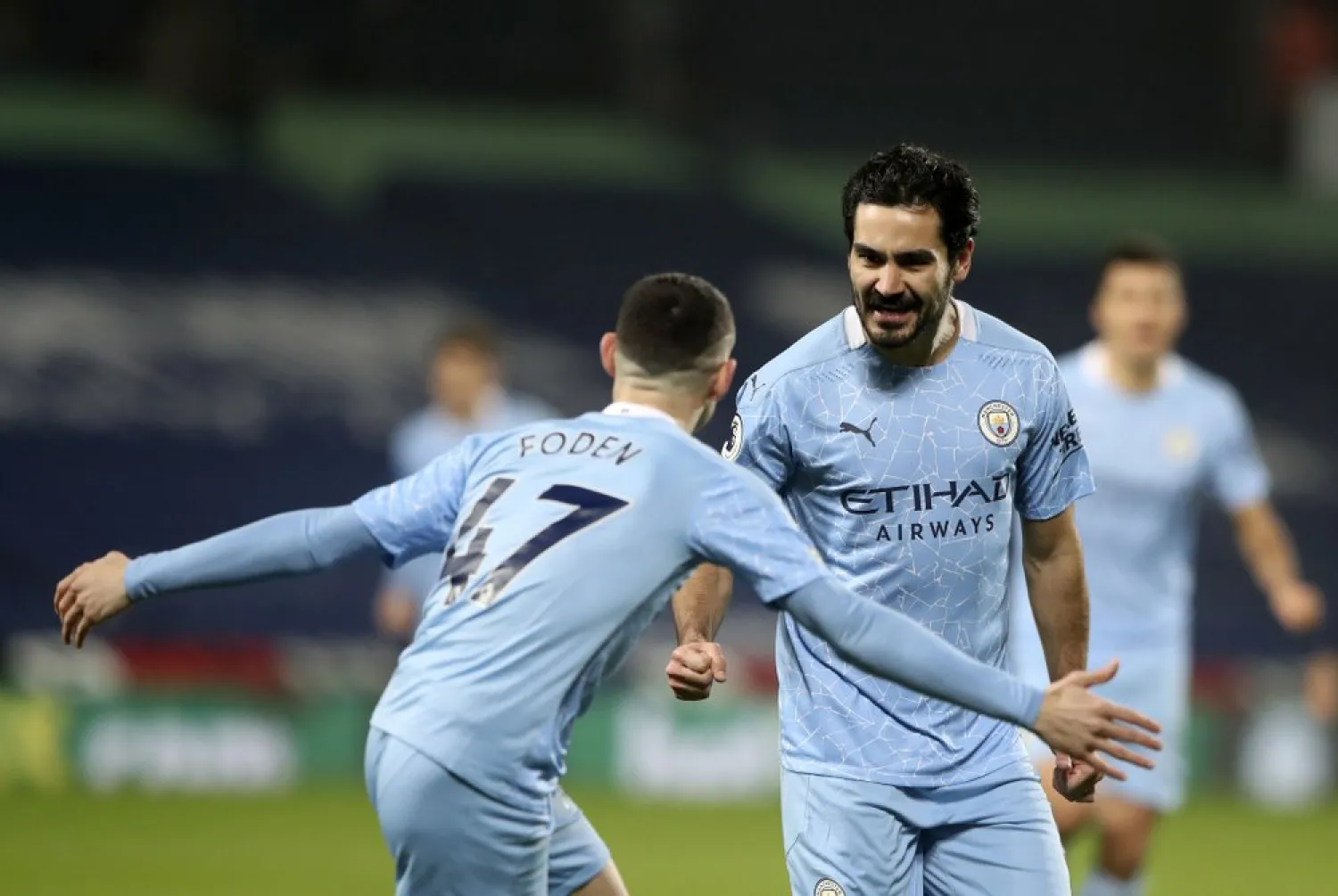Manchester City's Ilkay Gundogan, center, celebrates with Phil Foden, front, after scoring his side's opening goal during the Premier League match against West Bromwich Albion, Jan. 26, 2021. (AP)
