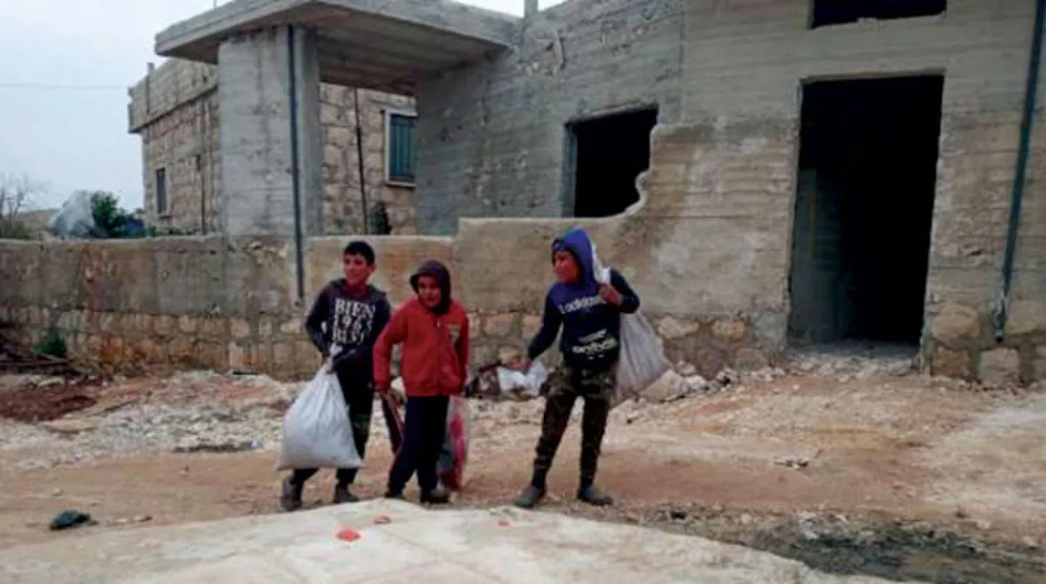 أطفال نازحون يحملون أكياس نايلون وبلاستيك في شمال غربي سوريا (الشرق الأوسط)