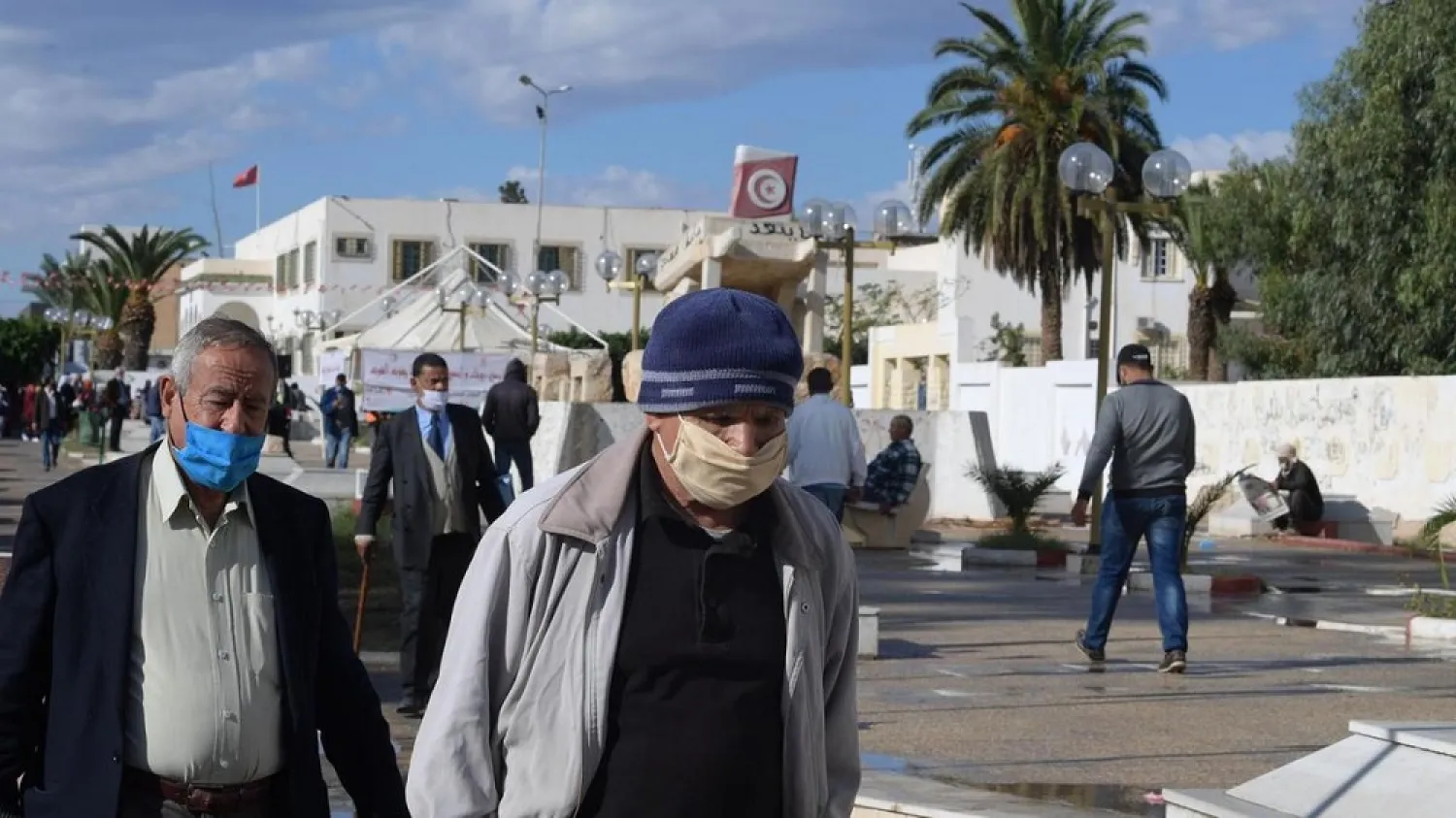 Tunisian men wearing protection masks against Covid-19 walk past the Mohamed Bouazizi's cart statue on October 27, 2020 in the central Tunisian city of Sidi Bouzid. (AFP)